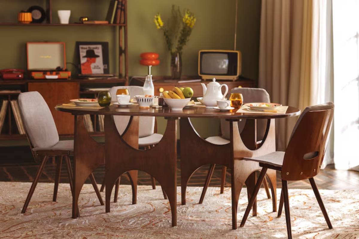 A stylish dining table set with a teapot, fruit bowl, and tea glasses, surrounded by vintage furniture and soft lighting.