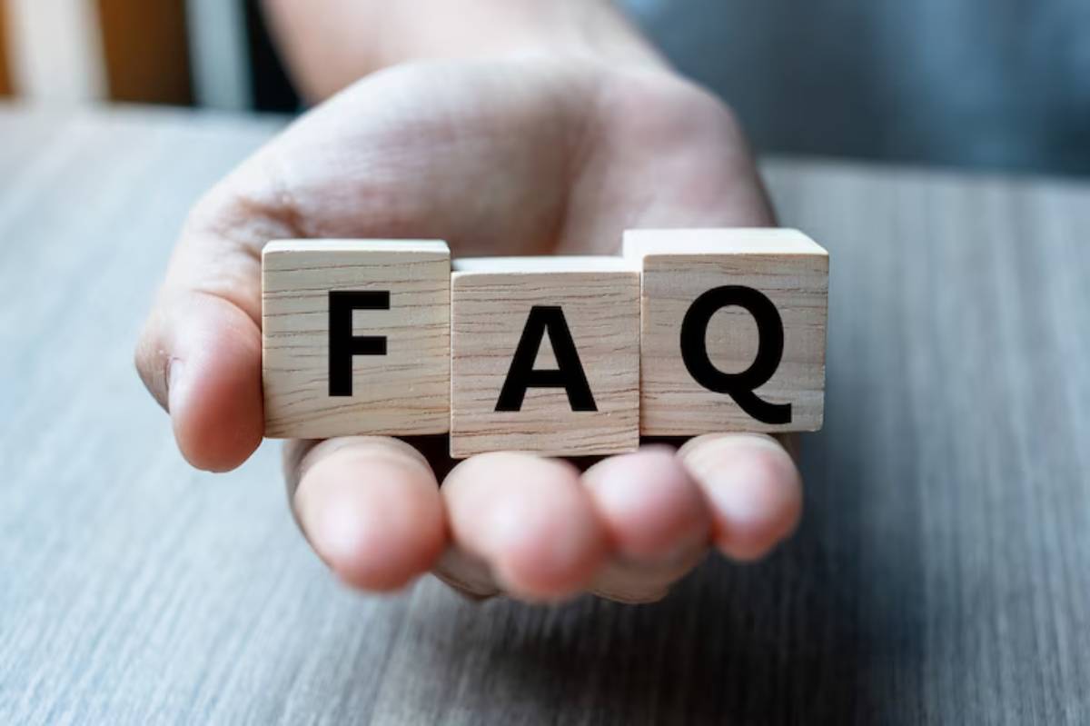 A hand holds wooden blocks displaying the letters F, A, and Q, symbolizing Frequently Asked Questions.