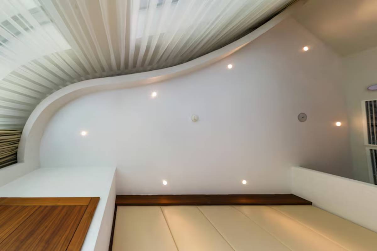 View of a curved ceiling with soft lighting and sheer fabric drapes, creating a cozy, modern interior atmosphere.