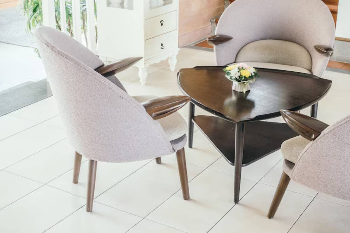 Cozy seating area featuring two stylish armchairs and a triangular wooden coffee table with a small flower vase in between.