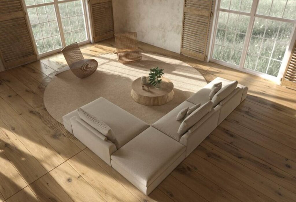 Modern living room featuring a beige sectional sofa, circular rug, wooden coffee table, and two curved chairs near large windows.