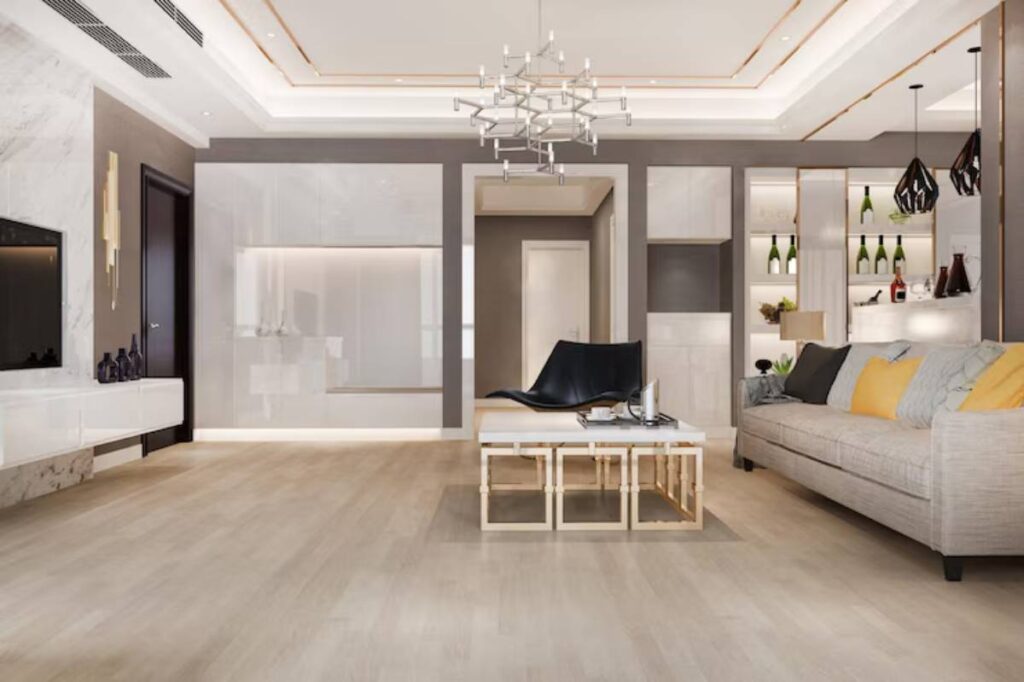 Modern living room featuring a stylish gray sofa, unique black chair, and elegant chandelier, with light wood floors and sleek decor.