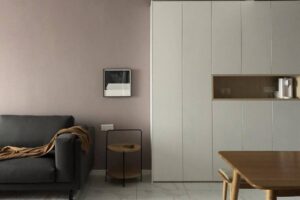 Cozy living space with a gray sofa, minimalist wall art, a sleek storage unit, and a wooden table. Soft, neutral color palette.