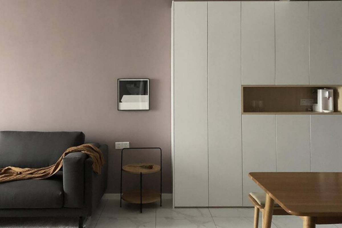Cozy living space with a gray sofa, minimalist wall art, a sleek storage unit, and a wooden table. Soft, neutral color palette.