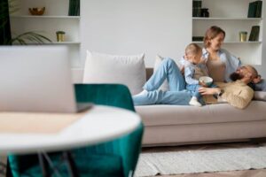 A cozy family scene on a beige sofa, with a child and adult sharing a bowl, surrounded by a modern, minimalistic living space.